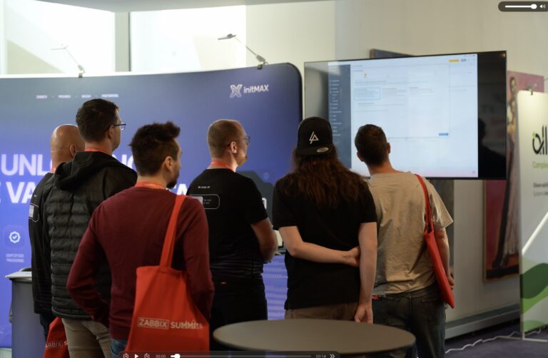Návštěvníci sledují ukázku u stánku initMAX – Zabbix Summit 2026, Riga